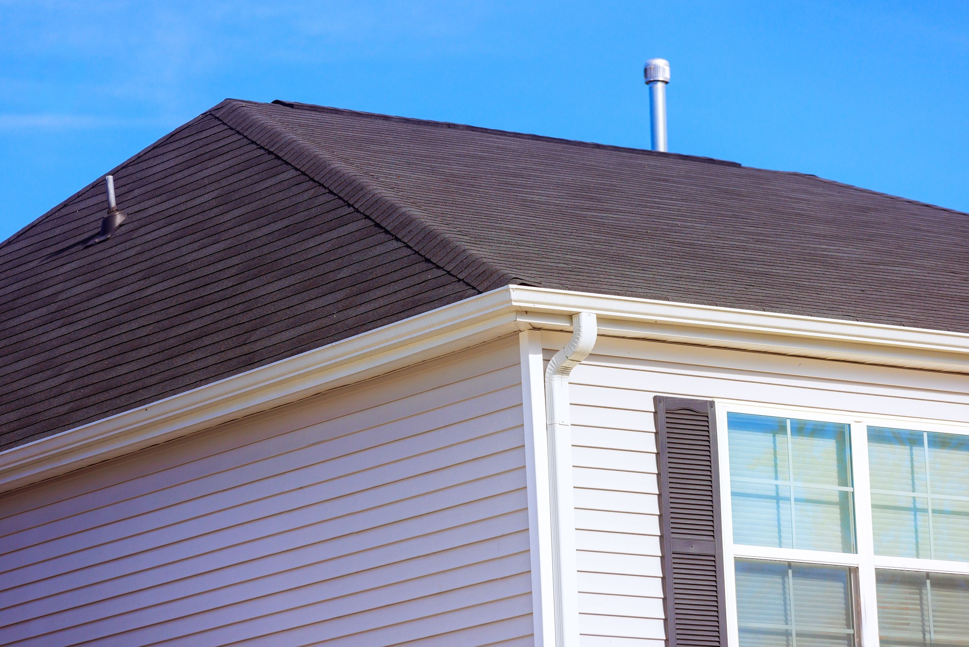 Well maintained residential roof on sunny day showcasing shingles, siding details